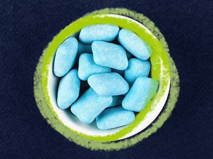 Light blue sugar-free chewing gum pieces in a small white bowl, viewed from above — xylitol is common in gum and other sugar-free products